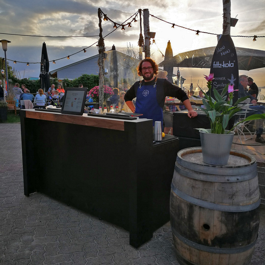 Black outdoor bar with wooden bartop.